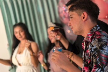 Group of happy friends with cocktails in their hands dancing cheerfully at birthday party