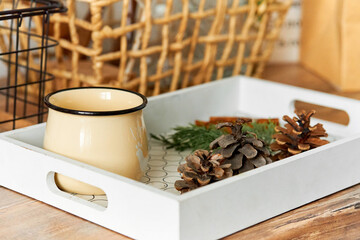 A tray with a jug of hot tea and pine cones. It will keep warm in cold autumn