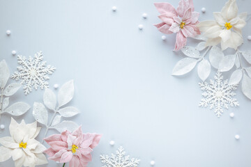 Christmas arrangement with festive baubles, poinsettia flowers and silver leaves on pastel background. Flat lay. Top view, copy space.