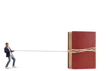 Full length profile shot of a young casual man pulling a giant book with a rope