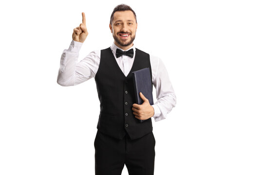 Cheerful waiter with a bow tie holding a menu and pointing up