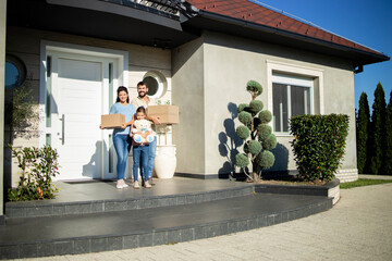 Portrait of happy caucasian family standing on porch of their new house ready to move in.