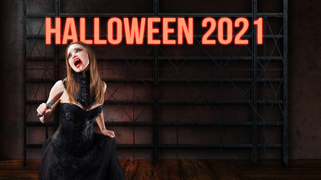 vampire in a dark dress and with a blody knife in front of a neon sign with the message HALLOWEEN 2021