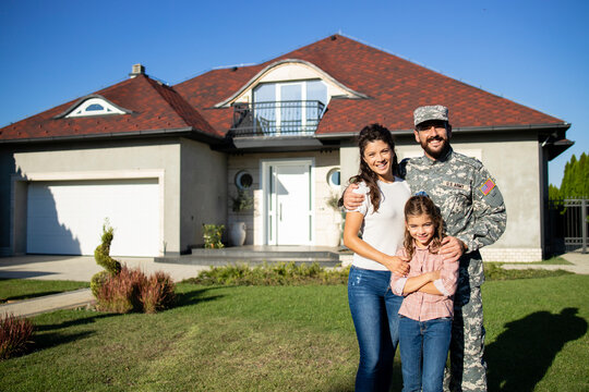 Portrait of happy american military family in front of their house.