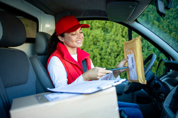 Female courier in van scanning parcels before delivering the shipment.