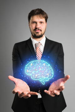 Businessman presenting an AI icon of a shining blue brain emitting energy and power on a virtual interface or computer screen
