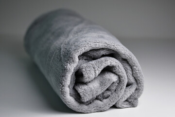 Comfort Rolled up grey coral fleece throw isolated on grey background. Fluffy warm, grey blanket...
