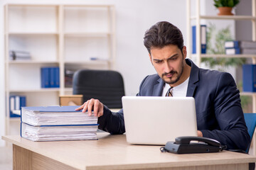Young handsome employee working in the office