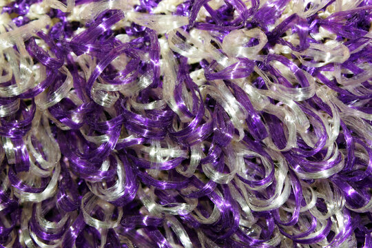 purple and white washcloth close-up. The view from the top. Texture. Background. Abstraction. Knitted washcloth. Self-care. The washcloth is made of propylene thread