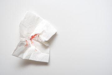 Used sheet of bloody toilet paper on white background close up, hemorrhoids and rectal bleeding concept, copy space