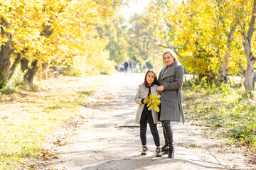 Obraz premium Young mother playing with her daughter in autumn park