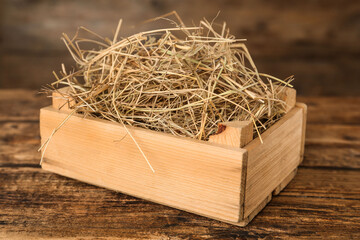 Dried hay in crate on wooden table
