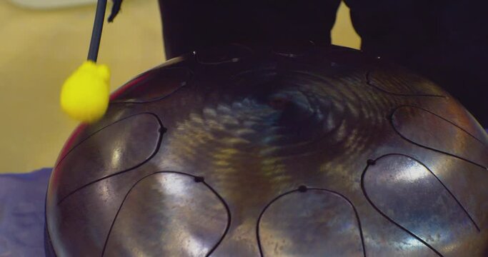 hobbies and leisure. drumsticks hit the metal handpan drum. close-up.