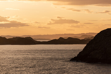 Golden sunset over an archipelago with wind turbines in the horizon.