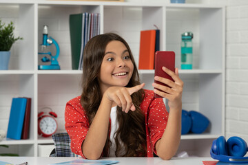 amazed teen girl making video pointing finger on selfie using mobile phone, content maker