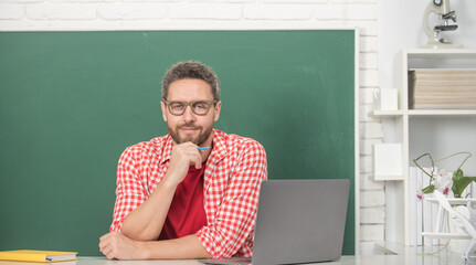 mature man teacher in glasses at blackboard, school