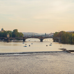 Catamarans on Vltava river near the Charles bridge at sunset light. Prague old town.