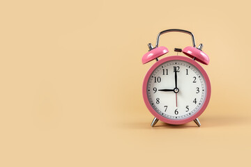 Pink alarm clock on a beige background. Time Concept. 9 o'clock. Copy space.