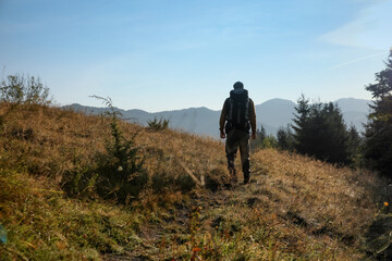 Obraz premium Tourist with backpack in mountains, back view. Space for text