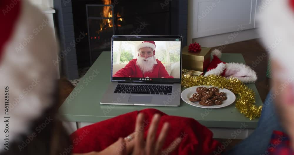 Sticker Rear view of caucasian couple wearing santa hats having a videocall on laptop during christmas