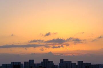 Fototapeta premium 都市の夜明け、早朝ビルの隙間から太陽が昇り辺りはオレンジ色に染まる。ビルはシルエットに浮かぶ