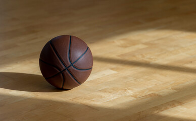 Basketball on hardwood court floor with natural lighting. Horizontal sport poster, greeting cards, headers, website and app