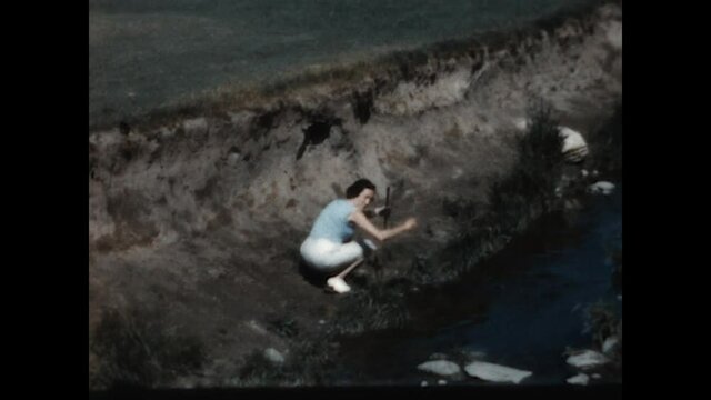 Found Ball 1958 - A woman finds her golf ball in a water hazard. 
