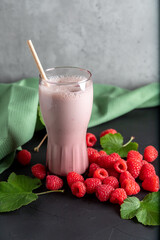 Delicious raspberry cocktail with yogurt on a dark background and fresh raspberries next to it.