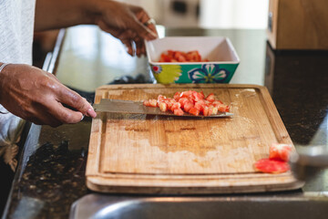 Manos de una mujer afroamericana mientras pica un tomate 