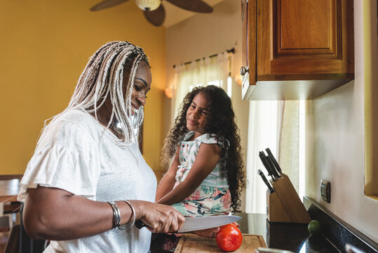 Madre e hija afroamericanas platicando mientras cocinan 