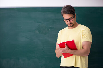 Young male student in front of blackboard