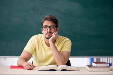 Young male student in front of blackboard