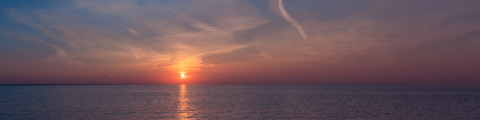 Naklejka na ściany i meble Sunset in the boundless horizon of the bay.