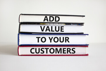 Add value to your customers symbol. Concept words 'Add value to your customers' on books on a beautiful white background. Businessman hand. Business, customers value concept.