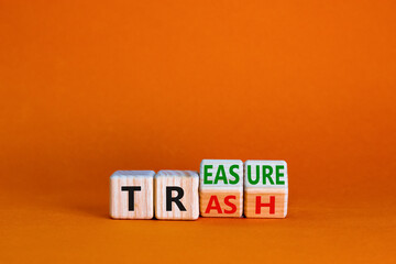 Trash to treasure symbol. Businessman turned cubes and changed the word trash to treasure. Beautiful orange table, orange background. Business, trash to treasure concept. Copy space.