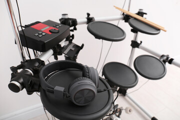 Modern electronic drum kit with headphones indoors. Musical instrument