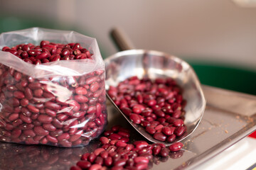 Red bean grains in a bag and a spoon. Red bean watered and ready to sell to the market. New alternative buying trend.