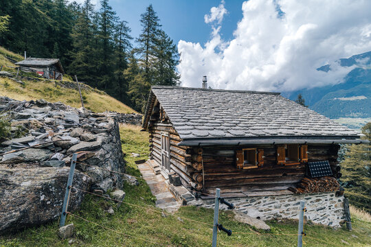 A wooden mountain hut or challet on a beautiful summer day. Blue sky, clouds, green pasture and mountain hut made of wood.