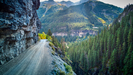 Dangerous dirt road in Rocky Mountains on narrow cliff edge in valley of mountains - Powered by Adobe
