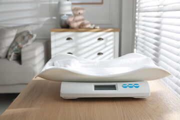 Modern digital baby scales on wooden table in room