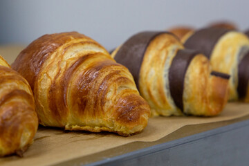 Many croissants with different flavors are freashly baked on the table. Manual production of handmade croissants and pastries