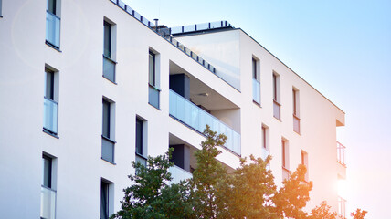 Inspiring view of the modern city. The wall of the apartment building   against trees. Apartment construction and ecology, view of  modern  building with blue sky and green tree. Sunlight