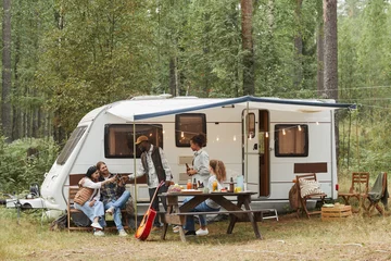 Wall murals Camping Wide angle view of young people enjoying outdoors while camping with van in forest, copy space