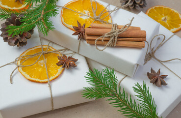 New Year's composition. On beige craft paper, gift boxes, dry orange slices, pine cones, cinnamon, cloves, spruce branches. Cozy Christmas concept.