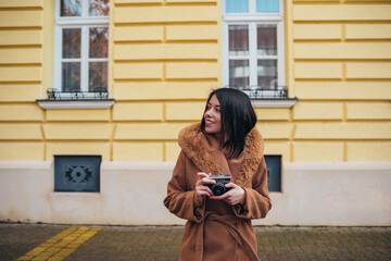 Hispanic woman using a retro camera while out in the city