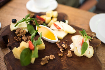 assorted aromatic cheeses in the form of cubes on a wooden board and white dishes a plate with herbs and sauce a dish in a restaurant