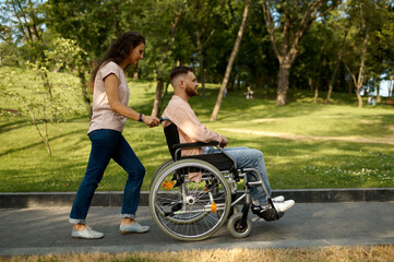 Fototapeta na wymiar Young couple with wheelchair walking in the park