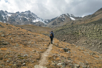 Fototapeta na wymiar A tourist walks along a trail with a view of the Caucasus Mountains, Elbrus region, Russia.