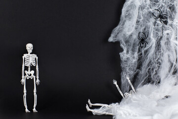 White skeletons on a black background. Skeleton and natural materials, wood, leaves, branches. The concept of the Day of the Dead. Happy Halloween. A postcard for All Saints' Day. A skeleton hanging 