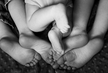 Feet of two children and one baby, black and white